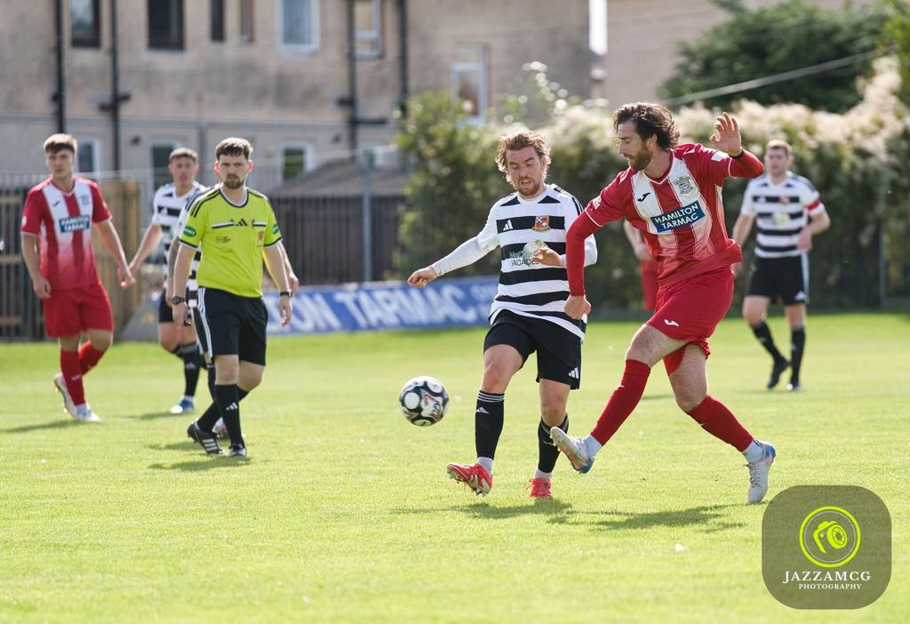 Hurlford United player in red and white stripes winning the ball from an opponent in black and white