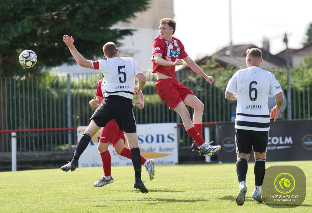Hurlford United player rising for a header among opponents in black and white